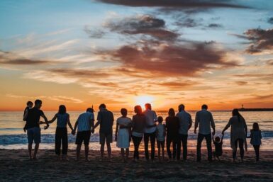 Un groupe de personnes alignées sur la plage au coucher de soleil