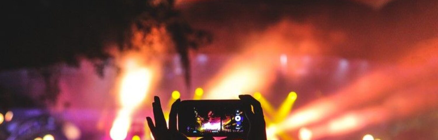 Une personne tient son téléphone portable pour filmer un concert de nuit