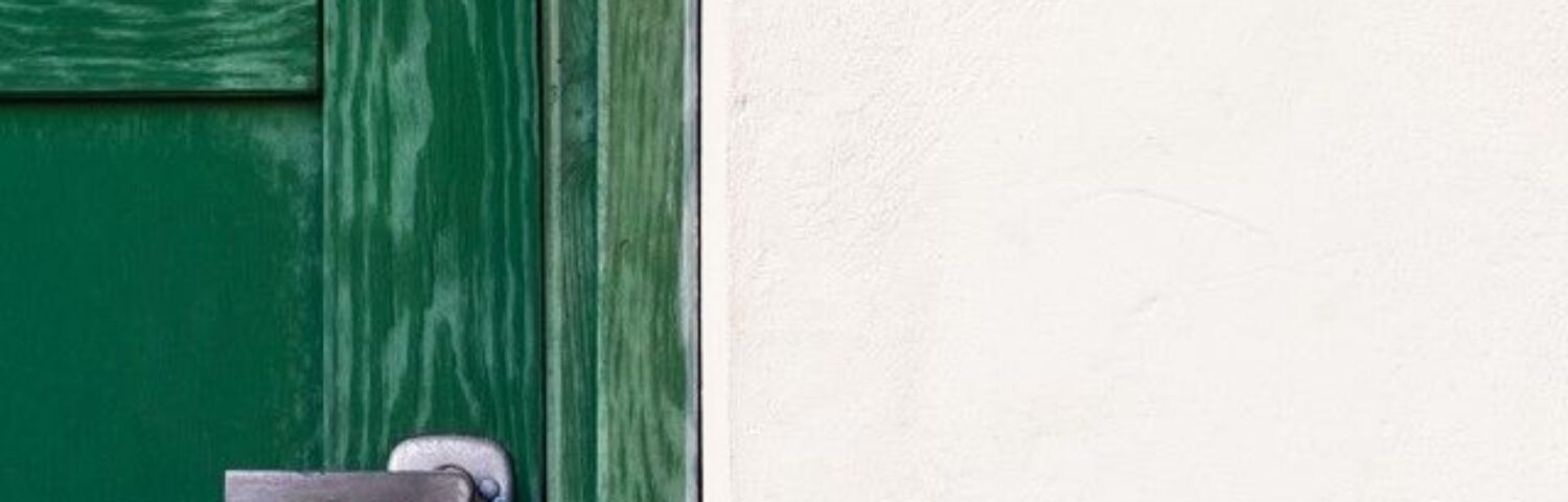 Une porte verte et sur un mur blanc