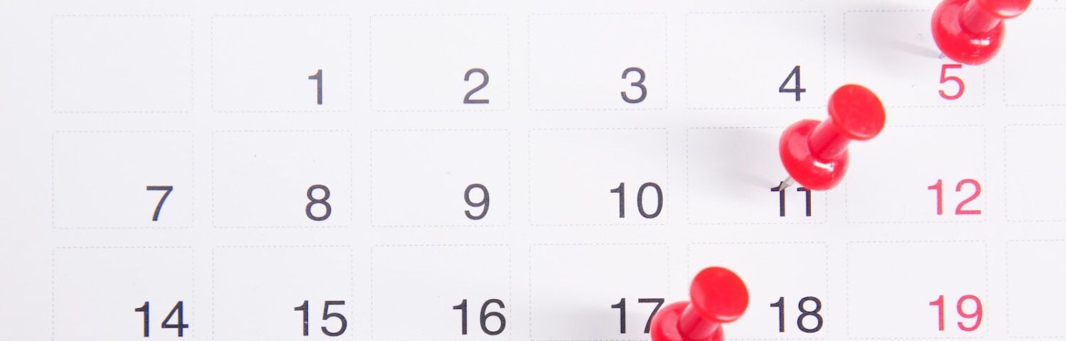 Un calendrier avec des boutons-poussoirs rouges épinglés